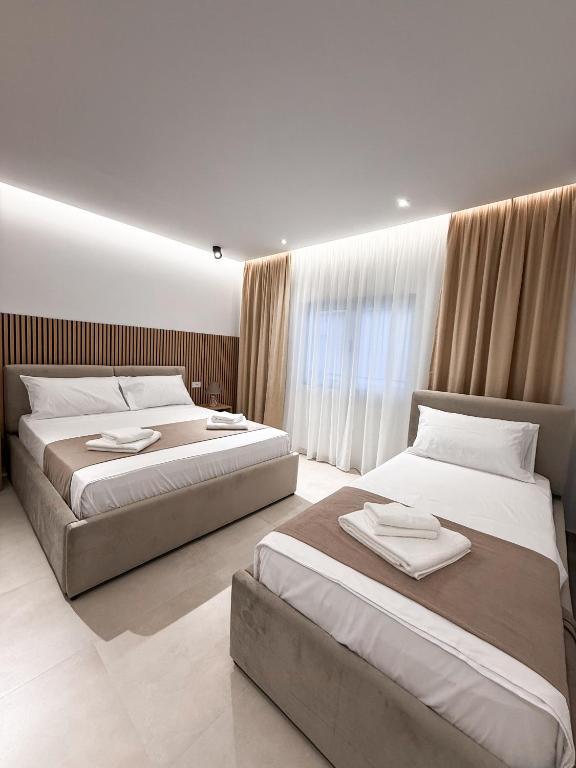 two beds in a hotel room with curtains at Hotel Alga Velipoje in Velipojë