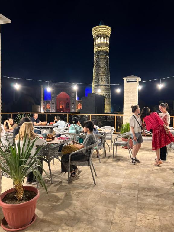 a group of people sitting at tables on a patio at night at Golden Minaret with Terrace in Bukhara
