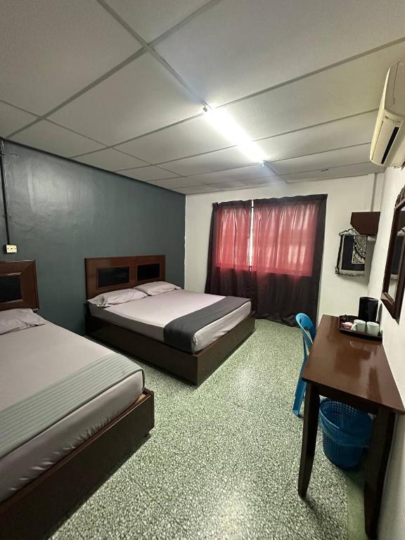 a hotel room with two beds and a desk and a desk at planet hotel mersing in Mersing