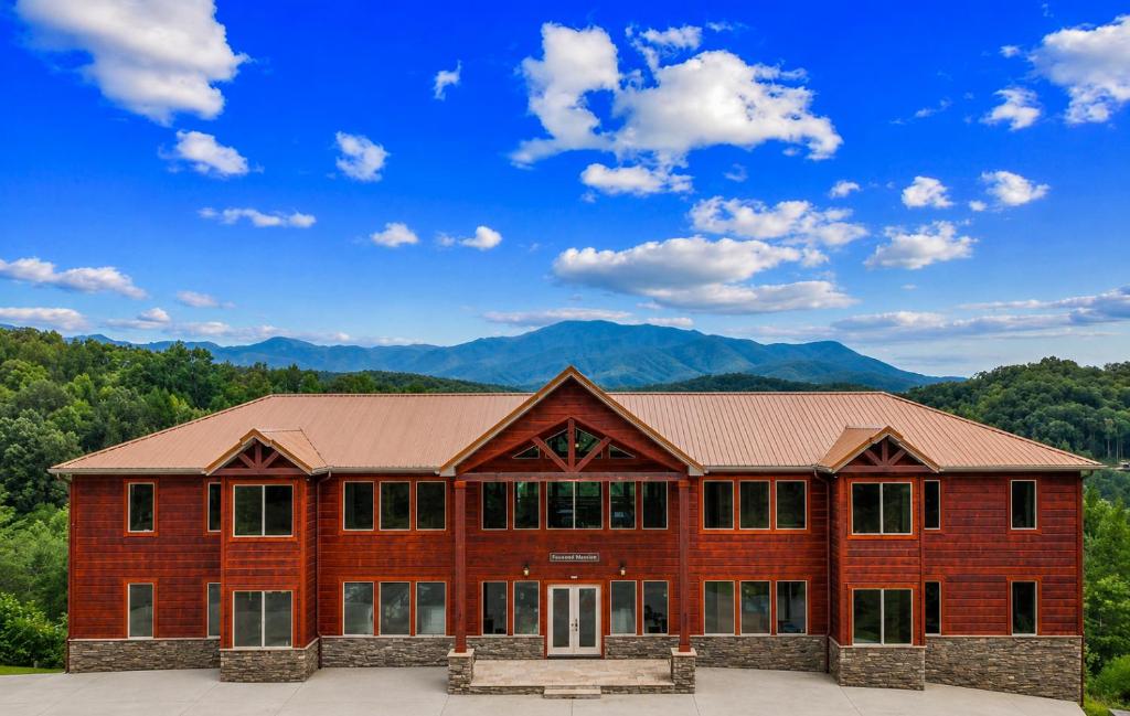 a large wooden building with mountains in the background at Foxwood Mansion Cabin in Pittman Center