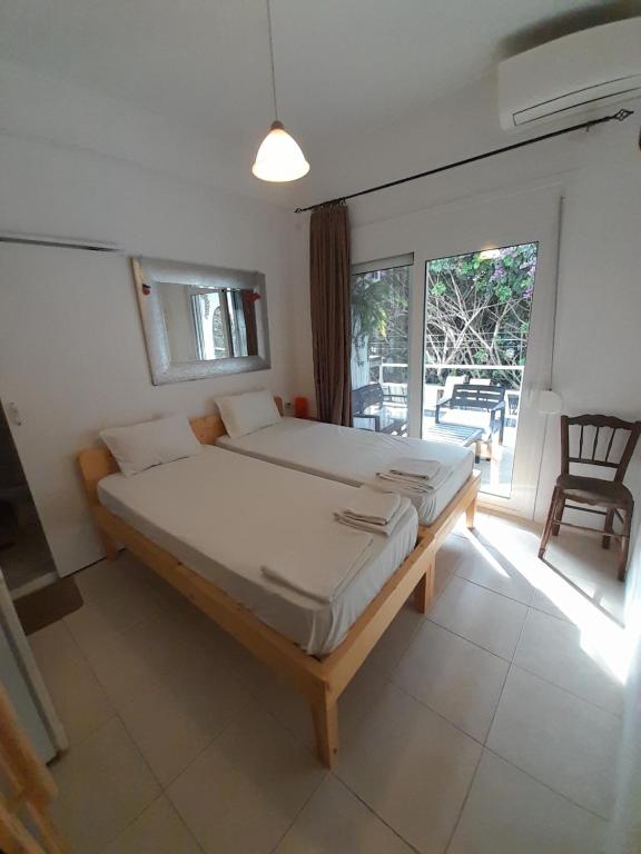 a bedroom with a large bed and a large window at Iliada Skiathos rooms in Skiathos