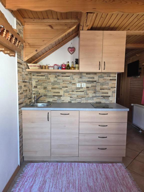 a kitchen with wooden cabinets and a stone wall at Apartments & Chalet Jurček in Luče