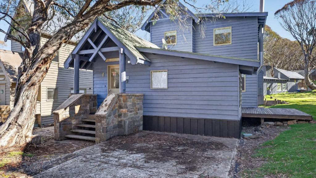 a blue house with a porch and a tree at Feathertop in Dinner Plain