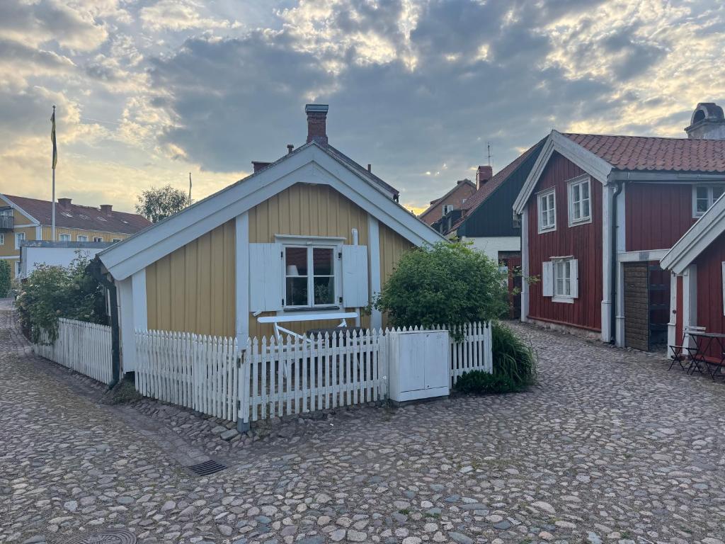 a small house with a white fence in a street at Båtmansstugan i Gamla Stan in Kalmar