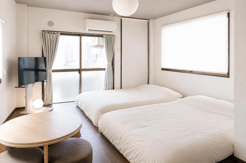 two beds in a room with a table and a tv at Bears Building in Kumamoto