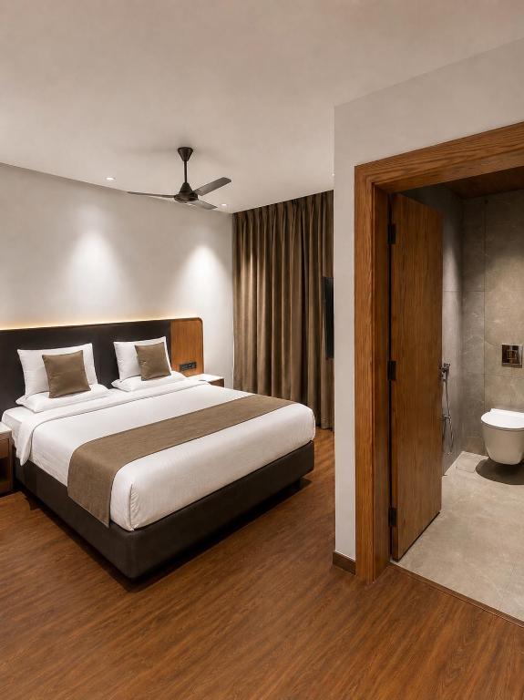 a bedroom with a large bed and a bathroom at Hotel Meridien Riverfront in Srinagar