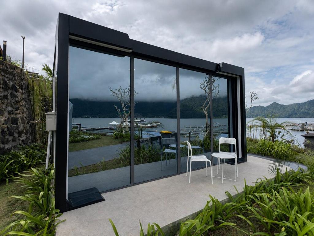 a house with large glass windows and white chairs at montevela glamping kintamani in Kubupenlokan