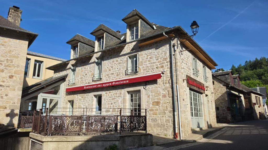 an old stone building with a red sign on it at L'hostellerie de la vallée in Gimel