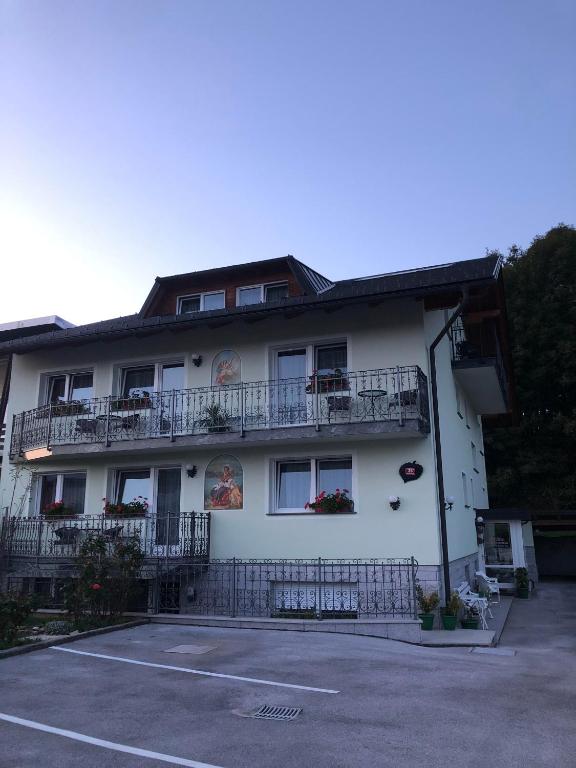 a large white building with balconies and a parking lot at Sobe apartma Dobe in Bled