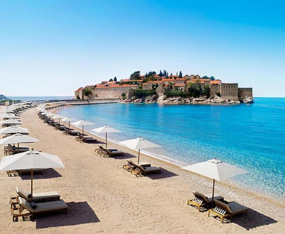 a row of umbrellas on a beach with the ocean at Lux Apartman Sofia in Sveti Stefan