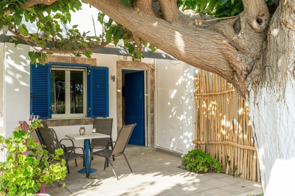 a patio with a table and chairs under a tree at Perasma Studios 12 in Kipri