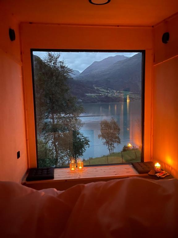 a bedroom with a large window with a view of a lake at Minihouse Stryn in Oppstryn