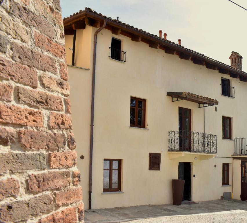 a white house with a red brick building at Langhem Suites Luxury Apartments in Castiglione Falletto