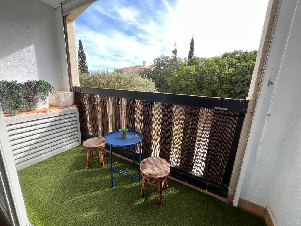 a small balcony with a blue table and two stools at Charmant studio cabine in Cap d'Agde