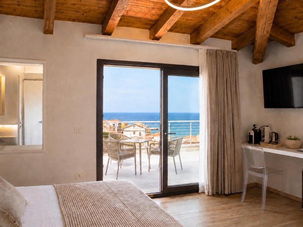 a bedroom with a large sliding glass door with a view of the ocean at Astra - Exclusive Rooms in Castelsardo