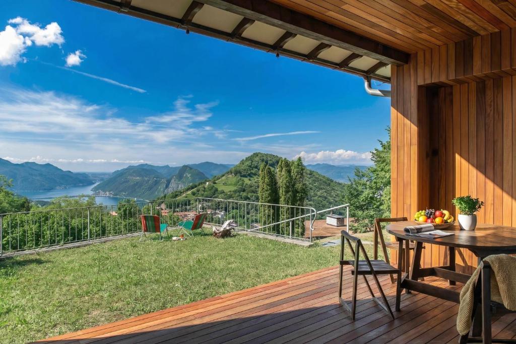 a patio with a table and chairs on a deck with a view at Luxury Nature Retreat Villa Planchette in Lugano