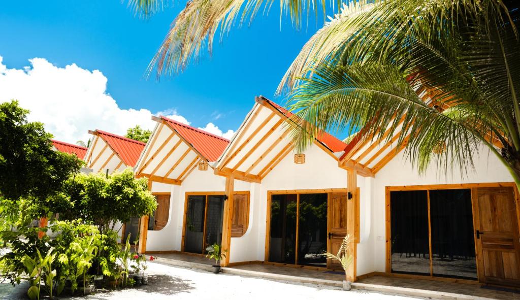 a house with a palm tree in front of it at Black Pearl View in Himandhoo 