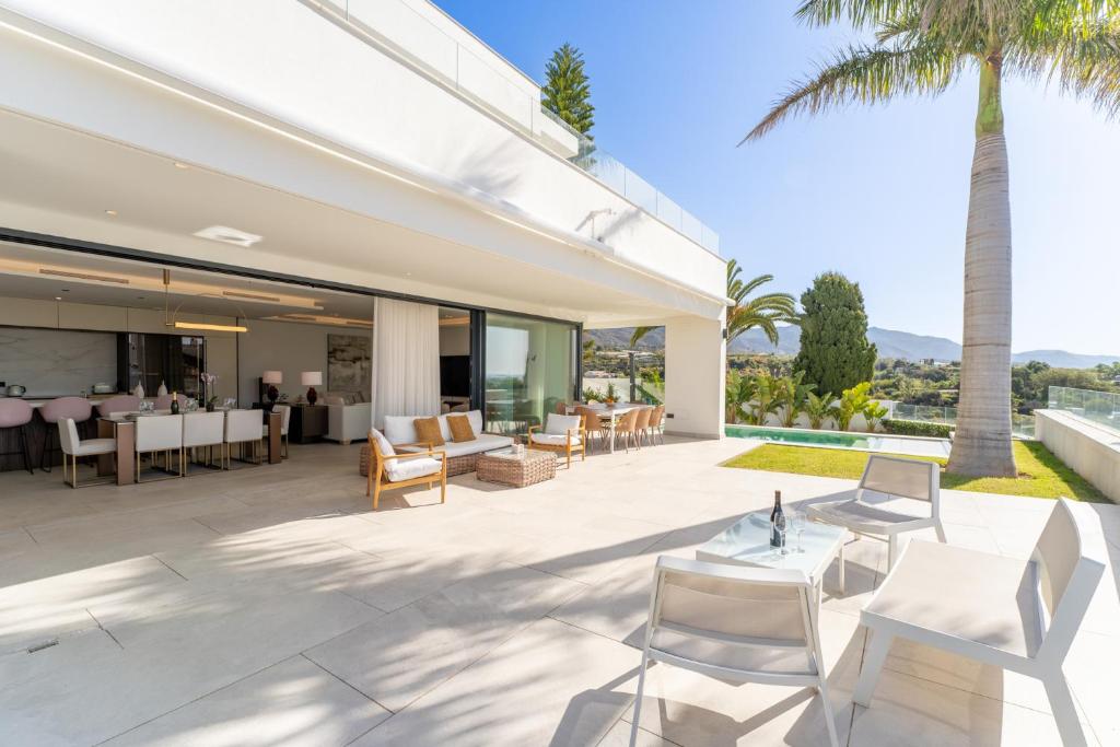 an outdoor patio of a house with white chairs and a table at Sea Gardens Villa in Nerja