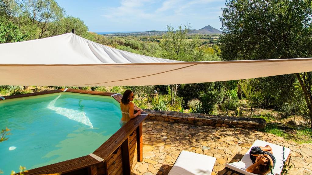 a woman standing next to a swimming pool under a canopy at Bioloco - sea, nature, pool in Castiadas