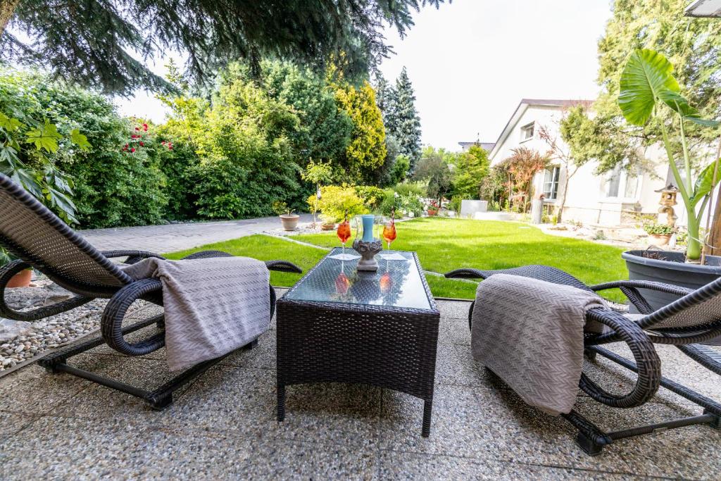 a patio with two chairs and a table with a vase on it at Apartman Karlina 100 m2 Terrace Garden in Šahy
