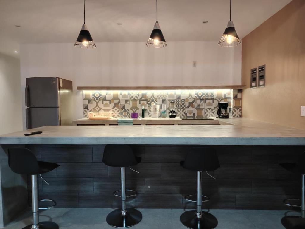 a kitchen with a large counter with bar stools at Depas las Palmas in Zihuatanejo