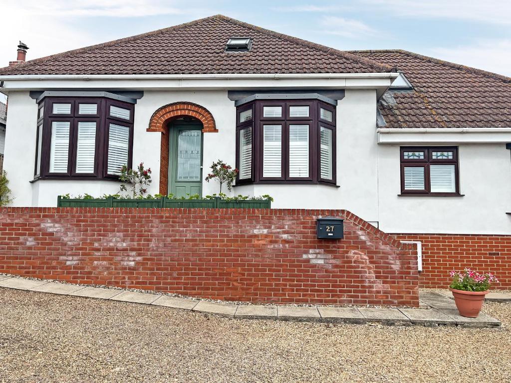a white house with black windows and a brick wall at Vine - Uk51860 in Ely