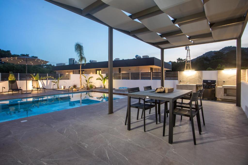 a patio with a table and chairs and a pool at Casadi Fileri Villa in Ialysos