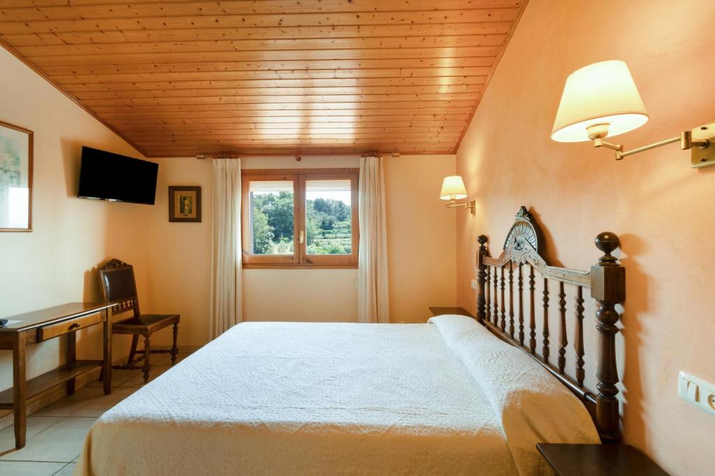 a bedroom with a bed and a desk and a window at Ball de Bastons in Avinyonet