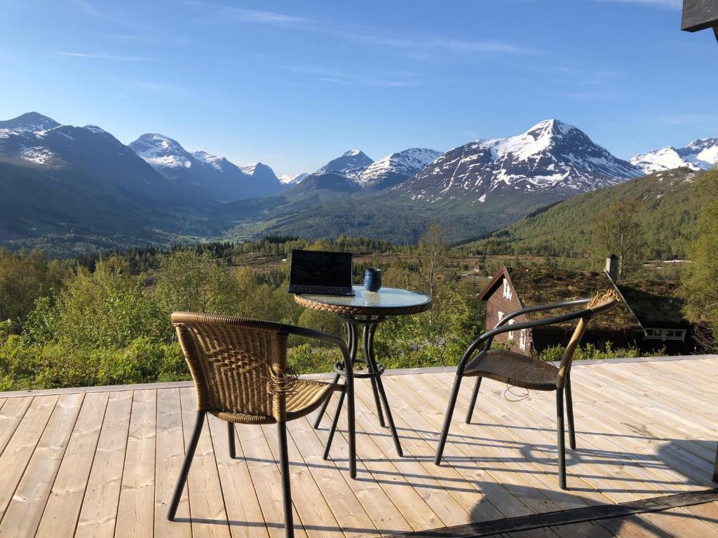 a table and two chairs on a deck with mountains at The View - Mountain cabin with stunning views in Stranda