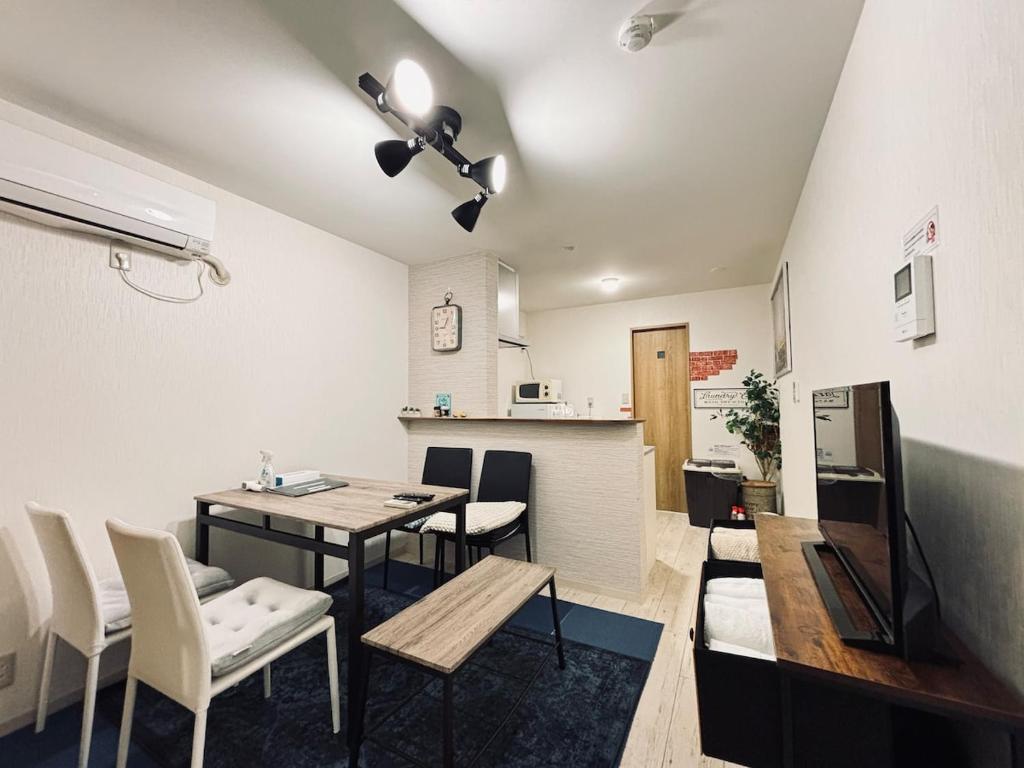 a living room with a table and chairs and a kitchen at Firmament Shimoshinjo in Osaka