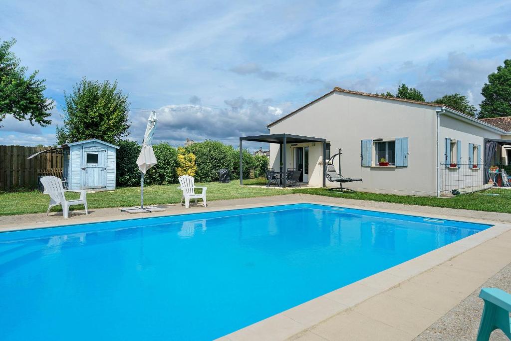 a swimming pool with two chairs and a house at Le Cocon Taillonais avec piscine in Saint-Ciers-du-Taillon
