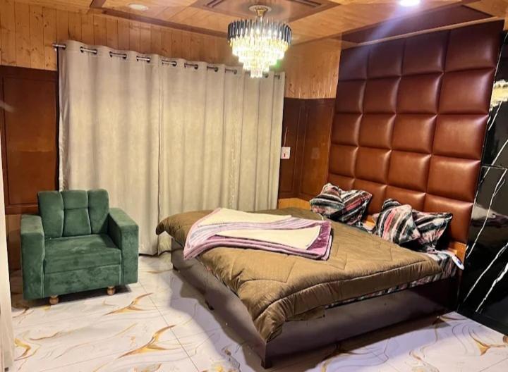 a bedroom with a large bed and a green chair at Snow and Saffron Hotel & Restaurant in Khor
