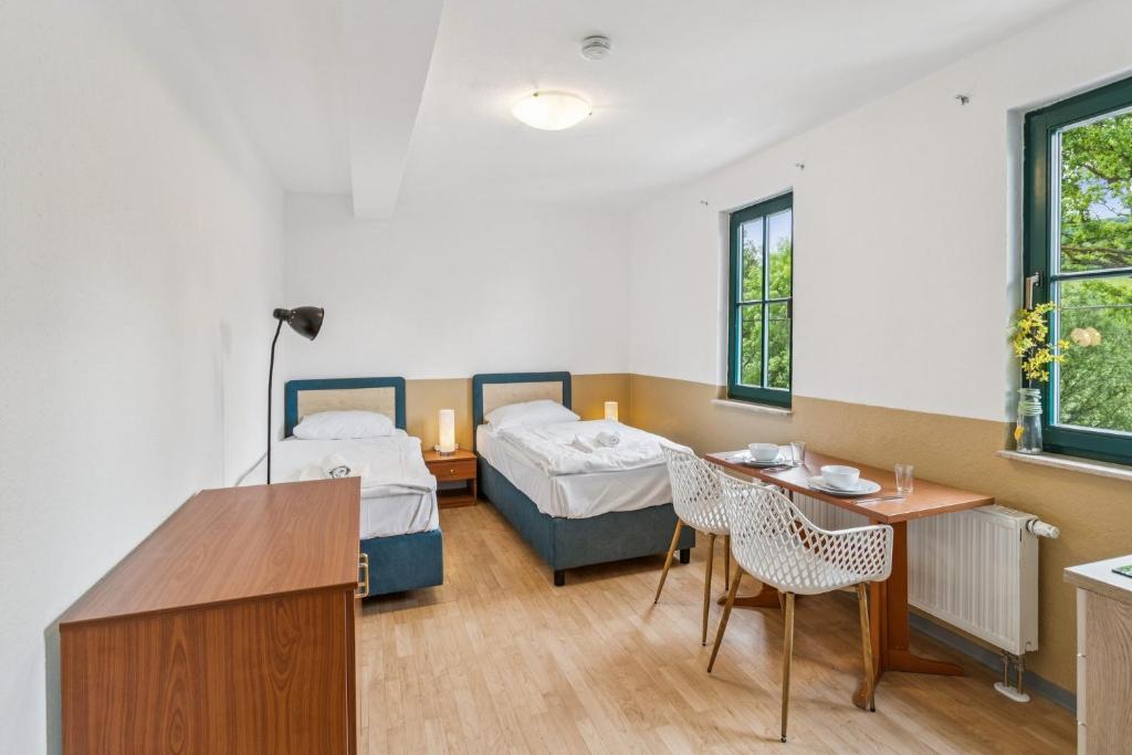 a room with two beds and a table and chairs at Jenapartments Pension - Studios mit Küche in Jena