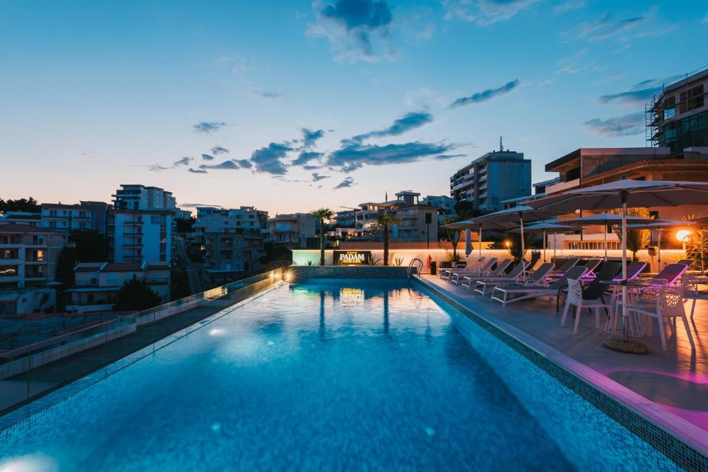 a swimming pool with chairs and umbrellas on a building at Padam Hotel & SPA in Ulcinj