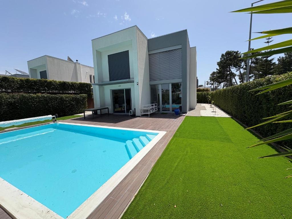 a house with a swimming pool in front of a yard at Aroeira Villa B&B in Charneca