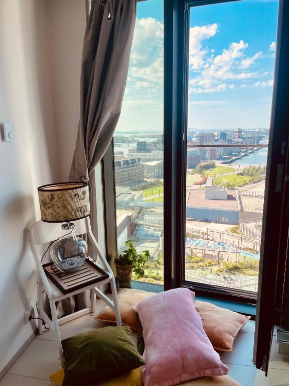 a room with a window with a chair and pillows at 1 studio seaview kalasatama Helsinki in Helsinki