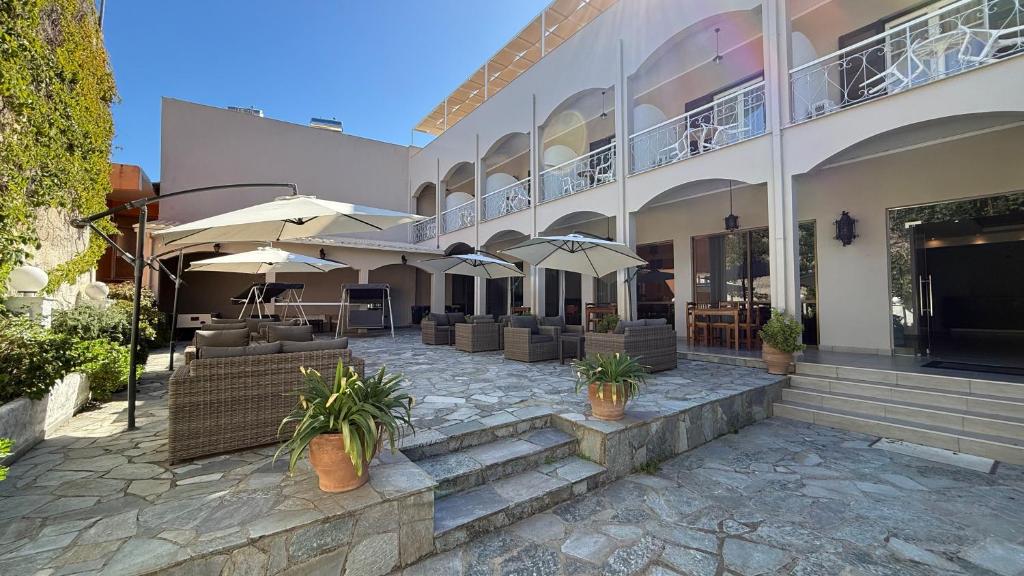 a building with a patio with chairs and umbrellas at Benitses Arches Hotel in Benitses