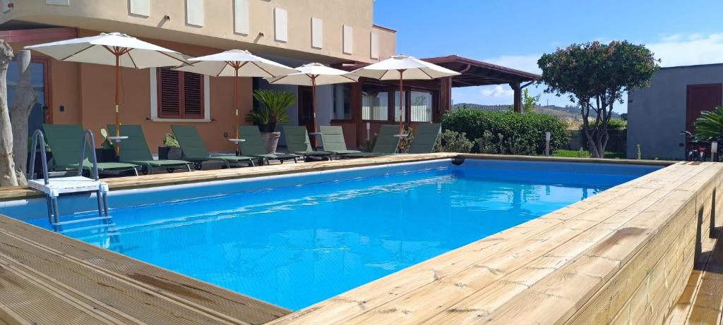 a swimming pool with blue water and umbrellas at Bed & Breakfast La Villetta in Botricello