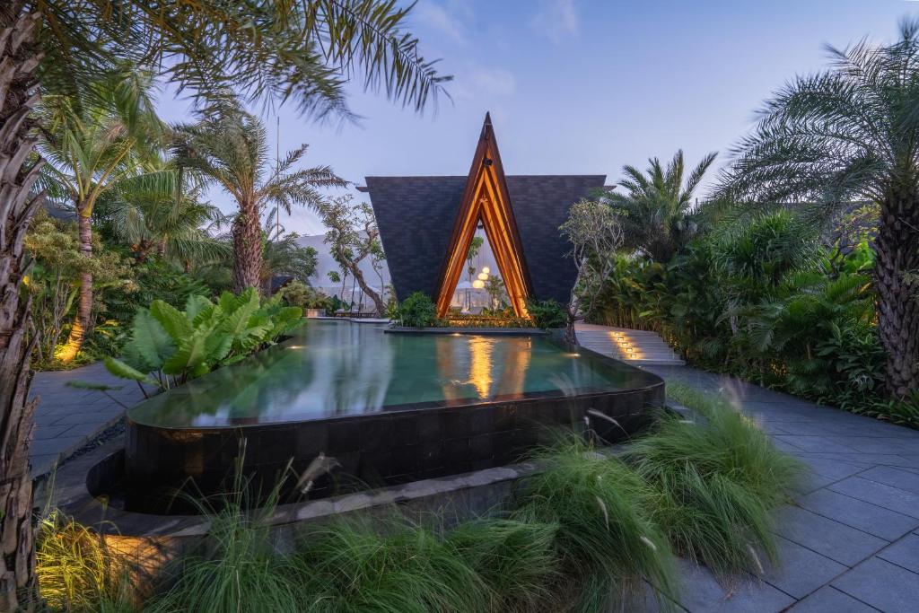 a swimming pool in the middle of a garden with a fountain at Nuju Uluwatu - Adults Only in Uluwatu