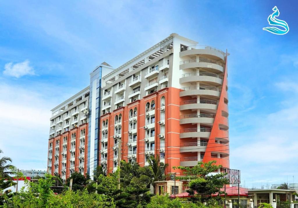 a tall red and white building with trees in front of it at The Sea Princess Hotel in Cox's Bazar