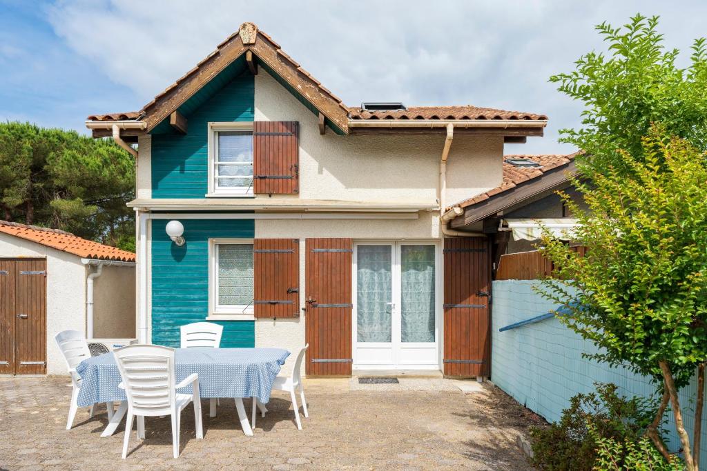 a blue house with a table and chairs at Escapade Landaise, Piscine in Capbreton