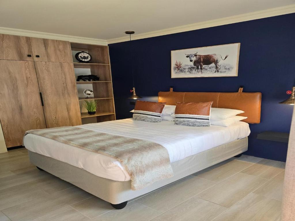 a bedroom with a large bed with a blue wall at NiNETEEN28 Guesthouse in Pietermaritzburg