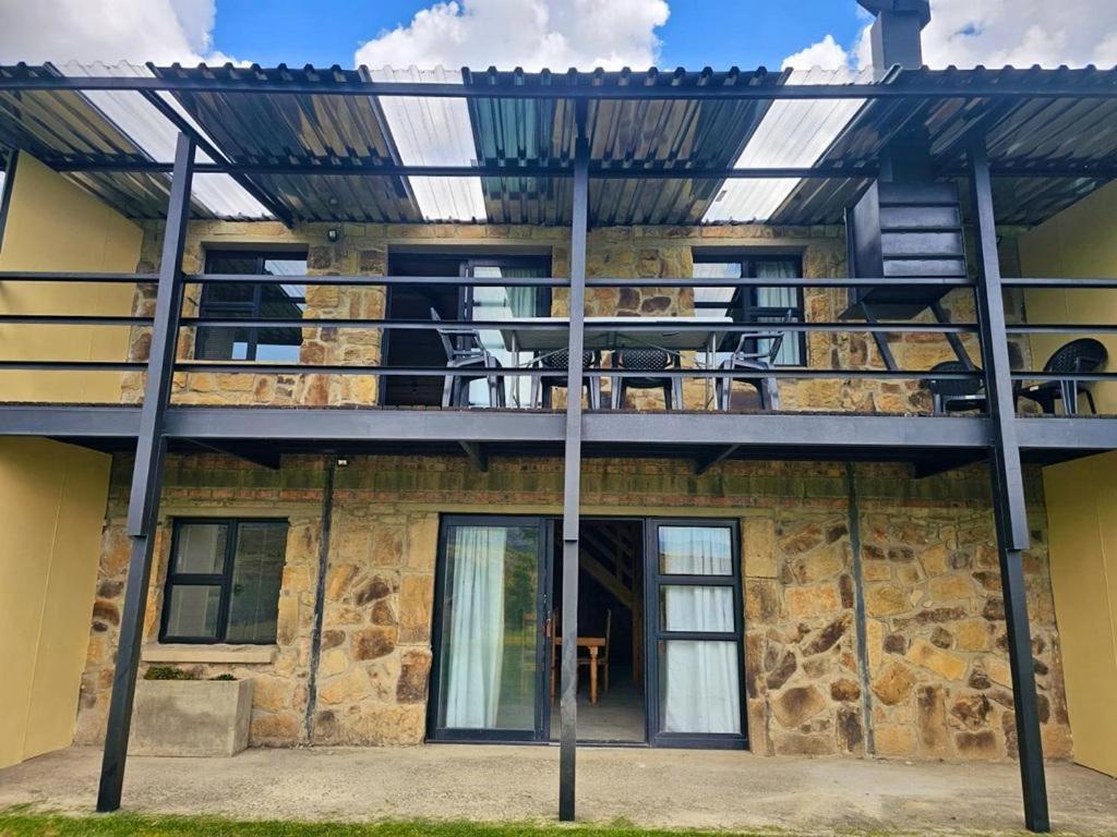 a building with a balcony with tables and chairs at Clarossouw in Clarens