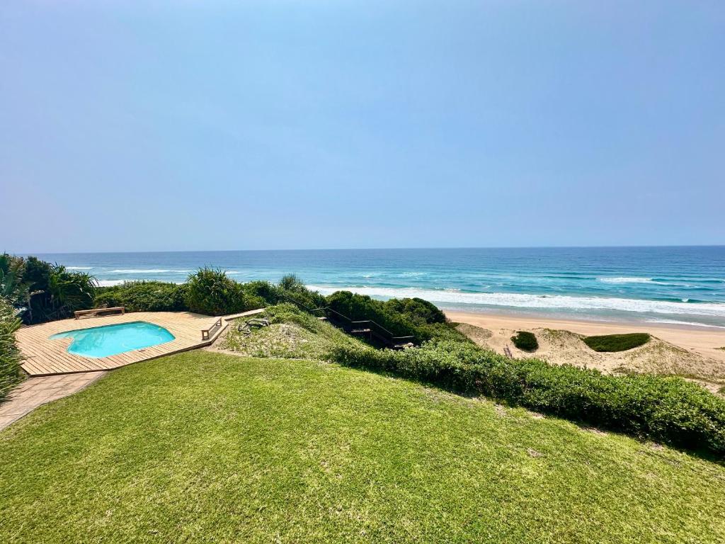 a swimming pool next to a beach with the ocean at Kangela 1 in Ponta Malangane