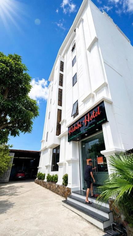 a man standing outside of a white building at Habibi Hotel in Sóc Sơn