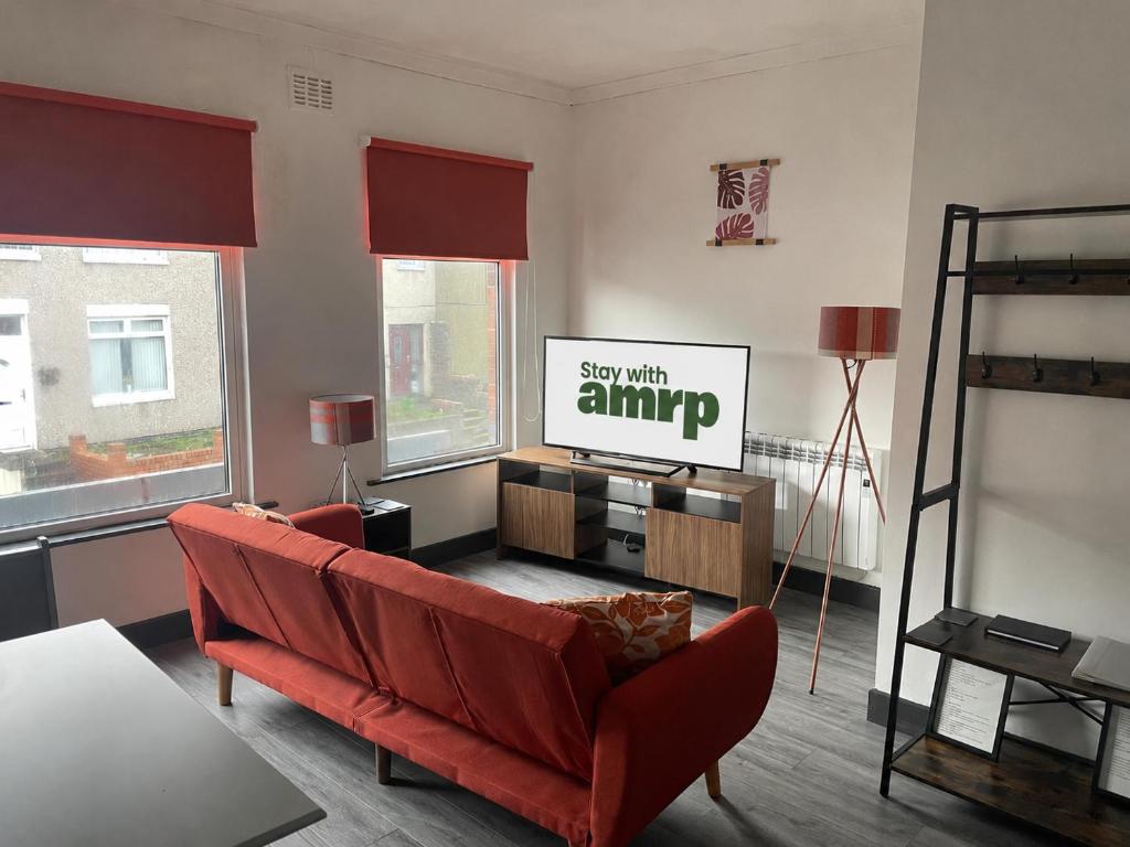 a living room with a red couch and a tv at 1 Bed Apartment Sleeps 3, Ferryhill Near Durham & WiFi in Ferryhill