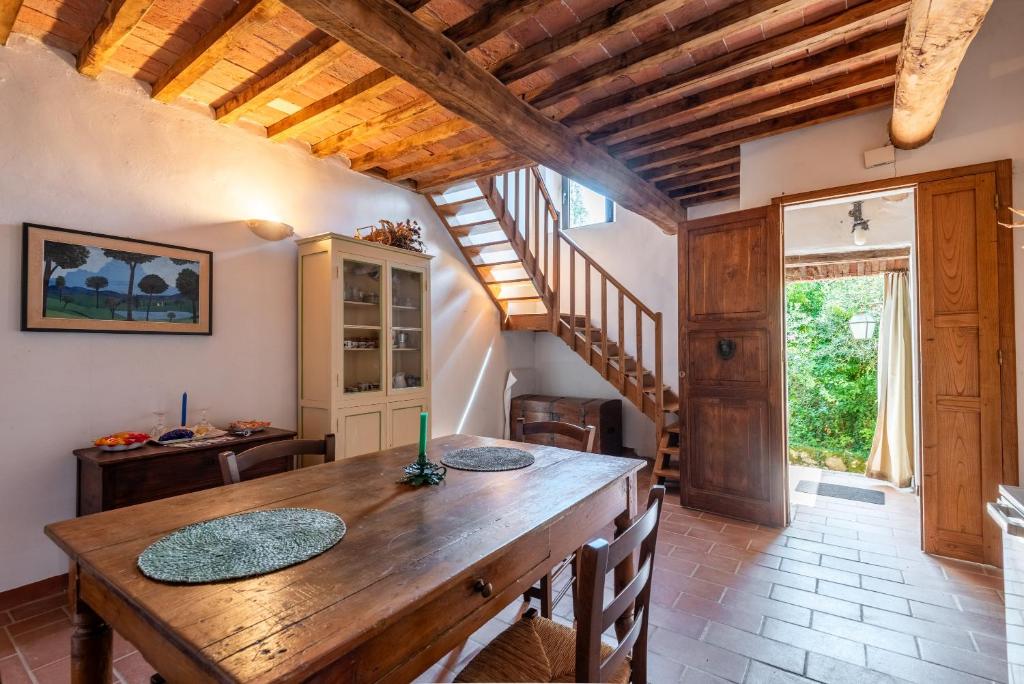 a dining room with a wooden table and a staircase at Appartamento Nobile Murlo in Murlo