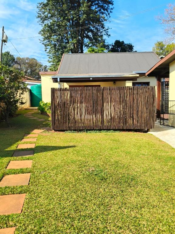 a fence in front of a house with a yard at The Museum Cottage in Sabie
