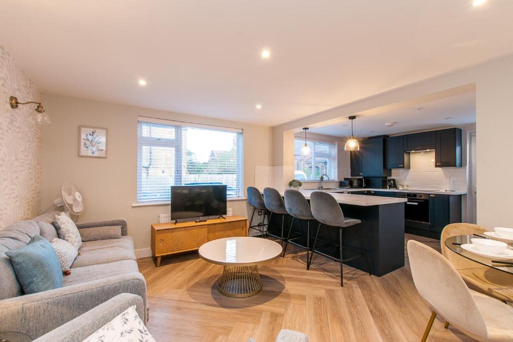 a living room with a couch and a kitchen at Marsh House - Modern Apartment With Hot Tub in Whitstable