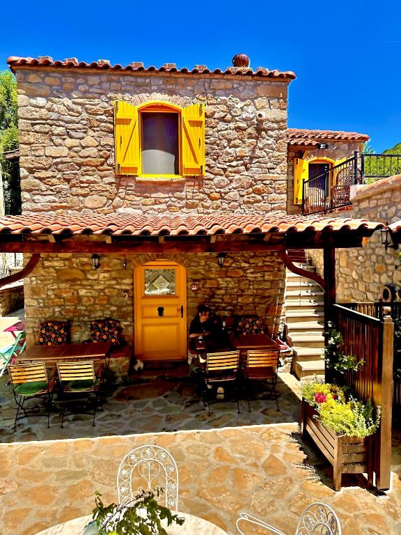 a stone house with a yellow door and chairs at Ilios Guest House in Gokceada Town